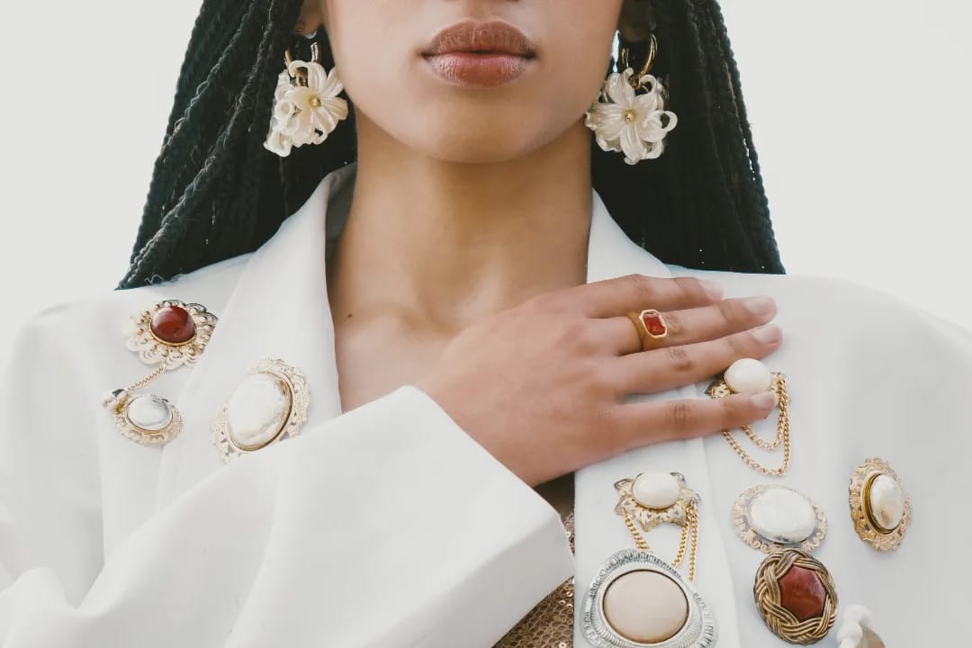 Ande Mafenuka styling detail — vintage brooches and cameos on a white blazer